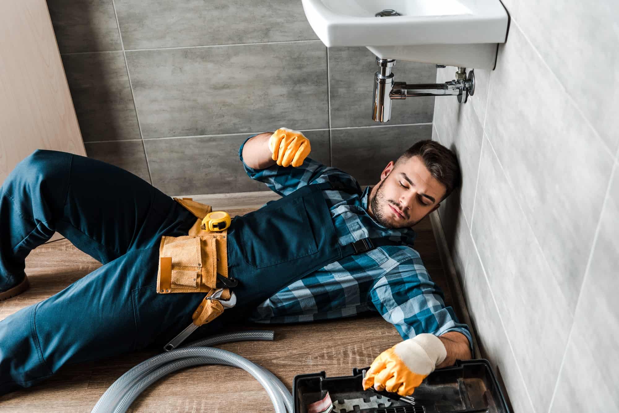 Plumber grabbing tools under sink